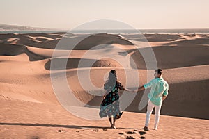 Couple walking at the beach of Maspalomas Gran Canaria Spain, men and woman at the sand dunes desert of Maspalomas