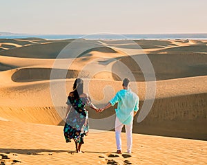 couple walking at the beach of Maspalomas Gran Canaria Spain, men and woman at the sand dunes desert of Maspalomas