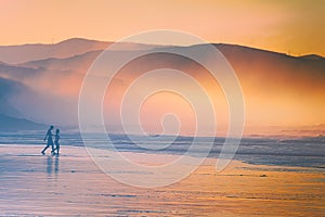 Couple walking on beach at sunset