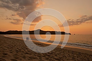 Couple walking on the beach during sunset. photo