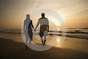 Couple walking on beach at sunset.