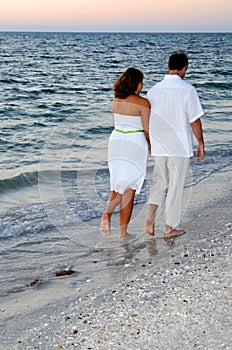 Couple walking on beach at sunset