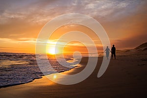 Couple walking on beach at sunset