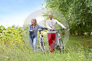 Couple walking with bicycle in hands