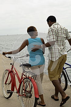 Couple Walking With Bicycles On Beach