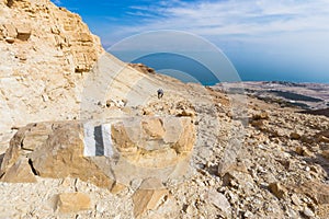 Couple walking desert trail down to Dead sea.