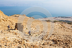 Couple walking desert trail down to Dead sea.