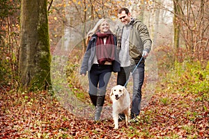 Couple Walking Dog Through Winter Woodland