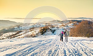 Couple walking down the snowy mountain in sunset time