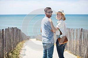 Couple walking on dune leading to beach