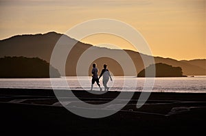 Couple walking on the edge of MassaguaÃÂ§u beach at dawn