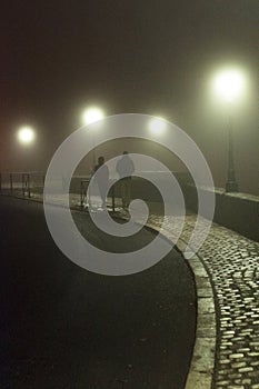 Couple walking by French battlements in the fog in AngoulÃªme.