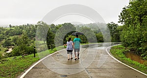 Couple walking hand in hand under umbrella in monsoon