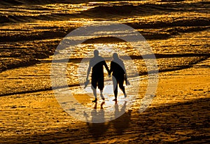 Couple walking holding hands beach