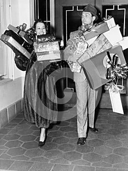 Couple walking and holding stacks of presents