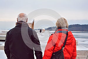 Couple walking on a long pier, on a cold winter day.