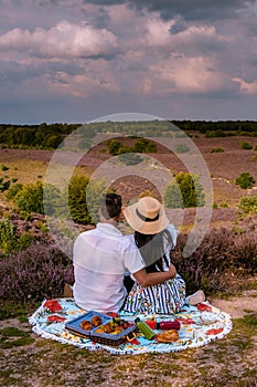 Couple walking in the meadows, Posbank national park Veluwezoom, blooming Heather fields during Sunrise at the Veluwe in