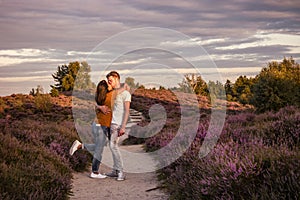 Couple walking in the meadows, Posbank national park Veluwezoom, blooming Heather fields during Sunrise at the Veluwe in