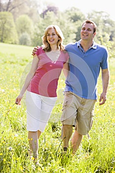 Couple walking outdoors holding flower smiling