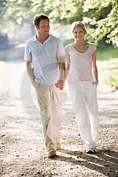 Couple walking outdoors holding hands and smiling