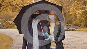 Couple walking in the park wearing protective masks