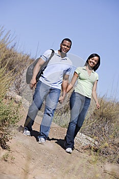 Couple walking on path holding hands and smiling