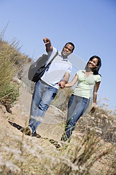 Couple walking on path holding hands and smiling