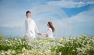 Couple walking in poppy field holding hands smiling, love and romance