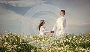 Couple walking in poppy field holding hands smiling, love and romance