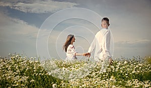 Couple walking in poppy field holding hands smiling, love and romance