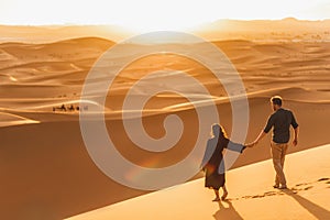 Couple walking in Sahara desert at sunset. View from behind, nature background