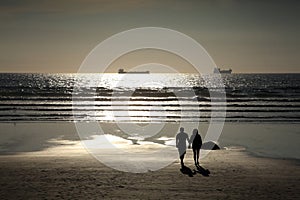 Couple walking on a silhouette sunset beach