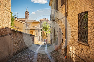 Couple walking a small alley in Castell`Arquato, Piacenza, Italy