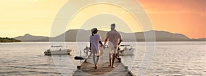couple walking on a wooden pier in the ocean at sunset in Thailand