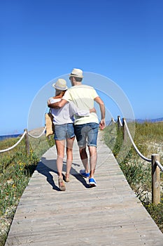 Couple walking on wooden pontoon going to the beach