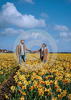 couple walking in yellow flower bed , men and woman in yellow daffodil flower field during Spring