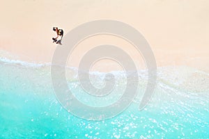 A couple walks along the Beach of Mauritius in the Indian ocean. Top view of the beach with turquoise water on the tropical island
