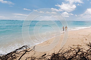 A couple walks along the Beach of Mauritius in the Indian ocean. Top view of the beach with turquoise water on the