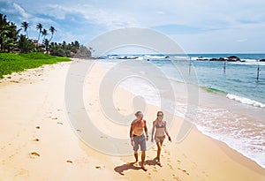 Couple walks along the tropical sandy beach