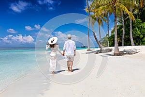 Couple walks down a tropical beach in the Maldives islands