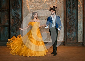 Couple walks in room old castle. Happy beauty woman fantasy princess in yellow dress and guy enchanted beast, horns on