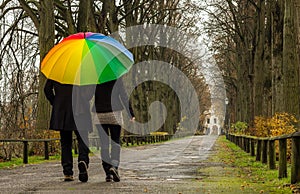 Couple walks under rainbow umbrella photo