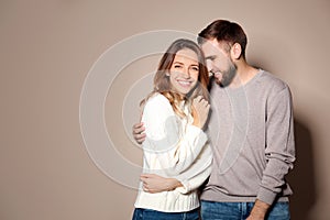 Couple in warm sweaters on beige background. Space for text