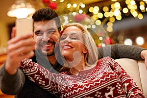 Couple in warm sweaters taking selfie picture with smartphone at