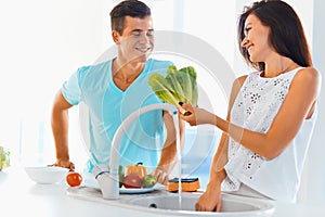 Couple washing organic vegetables together
