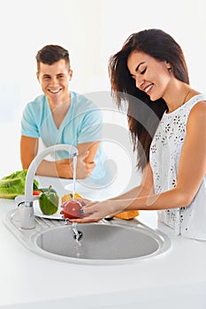 Couple washing vegetables in the kitchen. Focus on the woman.