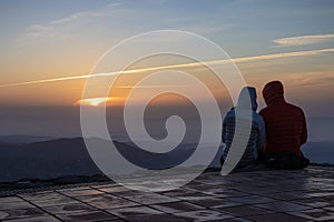 Couple watching an amazing sunrise from the top of La Mola Mountain in the Parc natural de Sant Llorenc del Munt i l`Obac