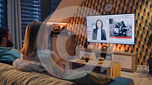 Couple watching breaking TV news about disaster