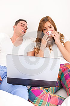 Couple watching dramatic movie in bed on laptop