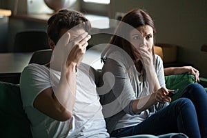 Couple watching horror movie sitting on couch at home
